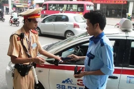 Cảnh sát giao thông tiến hành xử phạt lái xe taxi vi phạm. (Ảnh: Việt Hùng/Vietnam+)