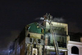 Cảnh sát Phòng cháy chữa cháy và Cứu nạn cứu hộ tiếp tục khống chế vụ cháy (ảnh chụp lúc 19h30). (Ảnh: Tuấn Đức/TTXVN)