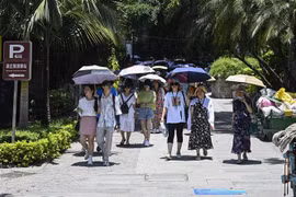 Người dân che ô tránh nắng trên đường phố tại tỉnh Phúc Kiến, Trung Quốc, ngày 24/7/2022. (Ảnh: AFP/TTXVN)
