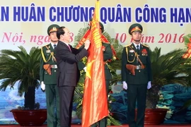 Chủ tịch nước Trần Đại Quang gắn Huân chương Quân công hạng Nhất lên lá cờ truyền thống của lực lượng vũ trang Thủ đô. (Ảnh: Nhan Sáng/TTXVN)