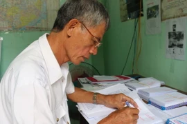 Cựu chiến binh Đào Thiện Sính viết thư cho thân nhân liệt sỹ. (Ảnh: Phan Sáu/TTXVN)