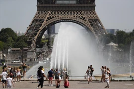 Người dân và khách du lịch giải nhiệt tại đài phun nước ở Paris, Pháp. (Ảnh: AFP/TTXVN)