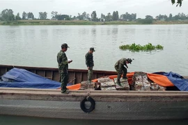 Cán bộ, chiến sỹ Đồn Biên phòng cửa khẩu Long Bình đang kiểm tra số phế liệu vừa bắt giữ. (Ảnh: Công Mạo/TTXVN)