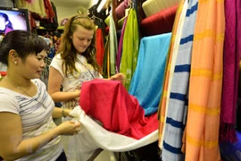 Khách du lịch tham quan và chọn mua sản phẩm lụa Vạn Phúc. (Ảnh: Thanh Hà/TTXVN)