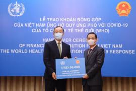 Thứ trưởng Bộ Ngoại giao Lê Hoài Trung trao tượng trưng số tiền 50.000 USD của Chính phủ và nhân dân Việt Nam đến Trưởng Đại diện Tổ chức Y tế Thế giới tại Việt Nam Kidong Park. (Ảnh: Lâm Khánh/TTXVN)