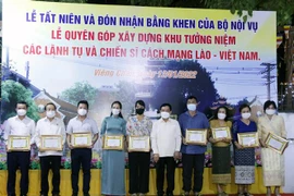Bộ trưởng Nội vụ Lào, ông Thongchan Manixay (giữa) với các cá nhân và tập thể người Việt có nhiều thành tích trong công tác cứu trợ và vận động cứu trợ cho người dân Lào gặp thiên tai, dịch bệnh trong thời gian qua. (Ảnh: Phạm Kiên/TTXVN)