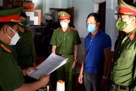Công an đọc quyết định bắt giữ đối tượng Cao Tiến Dũng. (Ảnh: TTXVN phát)