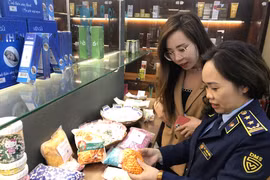Cán bộ Tổng cục Quản lý thị trường hướng dẫn cách nhận biết hàng giả. (Ảnh: Đức Duy/Vietnam+)