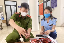 Lực lượng Công an và Quản lý thị trường kiểm tra hàng hóa vi phạm. (Ảnh: PV/Vietnam+)