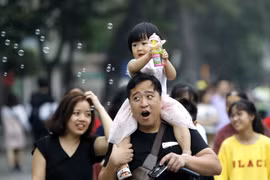 Phụ huynh đưa con em đến vui chơi trên phố đi bộ Hồ Gươm. (Ảnh: Văn ĐiệpTTXVN)