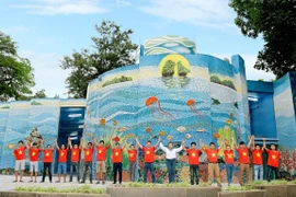 Họa sỹ Nguyễn Thu Thủy cùng các cộng sự thực hiện tác phẩm gắn gốm nghệ thuật Nhà Gương. (Ảnh: Đinh Thuận/TTXVN)