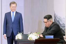 Nhà lãnh đạo Triều Tiên Kim Jong-un (phải) viết sổ lưu bút trước cuộc hội đàm thượng đỉnh với Tổng thống Hàn Quốc Moon Jae-in ở làng đình chiến Panmunjom. (Nguồn: Yonhap/TTXVN)