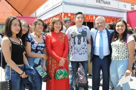 Đại sứ Nguyễn Hoài Dương và Phu nhân chụp ảnh với các bạn trẻ Mexico trước gian hàng Việt Nam. (Ảnh: Việt Hùng/Vietnam+)