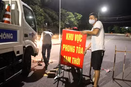 Lực lượng chức năng tháo gỡ biển hiệu phong tỏa Tổ 5A, Khu phố 1, phường Đông Lễ. (Ảnh: Nguyên Lý/TTXVN) 