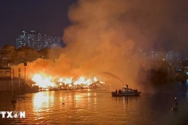 Cảnh sát Phòng cháy chữa cháy sử dụng ca nô chuyên dụng để phun nước vào đám cháy. (Ảnh: TTXVN)