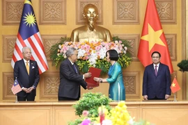 Tổng Giám đốc Thông tấn xã Việt Nam Vũ Việt Trang và Tổng biên tập Hãng thông tấn quốc gia Malaysia (BERNAMA) Khairdzir Md Yunus trao đổi Thỏa thuận hợp tác nghiệp vụ giữa Thông tấn xã Việt Nam và Hãng thông tấn quốc gia Malaysia. (Ảnh: Dương Giang/TTXVN)