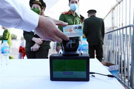 Người dân trước khi vào sân sẽ phải dùng thẻ CCCD gắn chip để thực hiện quét mã, chỉ những người hiện kết quả màu xanh (đã tiêm đủ 2 mũi) mới đủ điều kiện vào sân. (Ảnh: Phạm Kiên/TTXVN) 