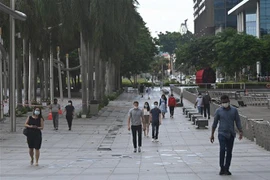 Người dân đeo khẩu trang và giữ khoảng cách phòng dịch COVID-19 tại Vịnh Marina, Singapore ngày 14/5/2021. (Nguồn: AFP/TTXVN) 