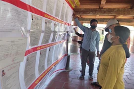 Hướng dẫn người dân trong thôn Kon Tum Kơ Pơng, phường Thắng Lợi, thành phố Kon Tum tìm hiểu thông tin bầu cử. (Ảnh: Dư Toán/TTXVN) 