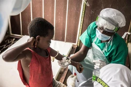 Nhân viên y tế lấy mẫu máu xét nghiệm cho em bé tiếp xúc với bệnh nhân mắc đậu mùa khỉ tại Zomea Kaka, Cộng hòa Trung Phi. (Ảnh: AFP/TTXVN)