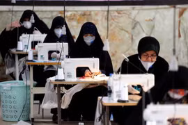 Phụ nữ may khẩu trang và đồ bảo hộ chống dịch COVD-19 tại Tehran, Iran. (Ảnh: AFP/TTXVN) 