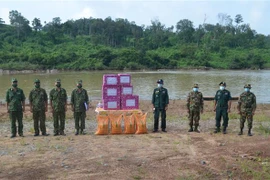 Đại diện Đồn biên phòng Ia O, Bộ chỉ huy biên phòng tỉnh Gia Lai (bên trái) trao hỗ trợ lương thực, thực phẩm, nhu yếu phẩm và vật tư y tế hỗ trợ công tác phòng, chống dịch cho đại diện lực lượng bảo vệ biên giới Campuchia. (Ảnh: Hồng Điệp/TTXVN) 