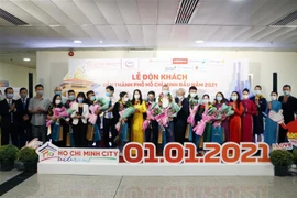 Hành khách và đại diện ngành Du lịch Thành phố Hồ Chí Minh tại Lễ đón khách đến Thành phố Hồ Chí Minh đầu năm 2021. (Ảnh: Mỹ Phương/TTXVN)