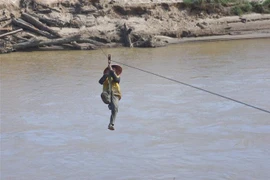 Người dân liều mình đu dây qua sông Pô Kô. (Ảnh: Khoa Chương/TTXVN) 