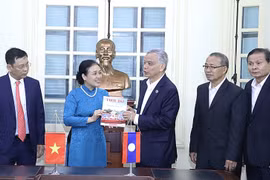 Bà Nguyễn Phương Nga tặng Chủ tịch Ủy ban Hòa bình và Đoàn kết Lào Sommad Pholsena cuốn đặc san "60 năm hữu nghị Việt Nam-Lào: Chung dãy Trường Sơn" của Tạp chí Thời Đại. (Nguồn: hanoimoi.com.vn) 