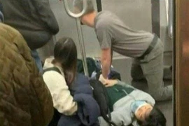 Hành khách sơ cứu cho một người bị thương sau vụ nổ súng trên tàu điện ngầm ở New York, Mỹ ngày 12/4/2022. (Ảnh: AFP/TTXVN)
