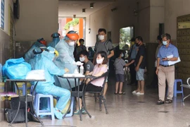 Lực lượng y tế túc trực để lấy mẫu xét nghiệm cho toàn bộ cư dân chung cư Thái An 2B, đường Nguyễn Văn Quá, phường Đông Hưng Thuận, Quận 12. (Ảnh: Đinh Hằng/TTXVN) 