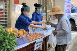 Đoàn viên thanh niên huyện Nhà Bè hỗ trợ người dân mua sắm thực phẩm tại siêu thị 2.000 đồng ở xã Hiệp Phước. (Ảnh: Hồng Giang/TTXVN) 