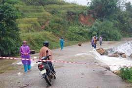 Người dân và lực lượng chức năng xã Măng Ri huyện Tu Mơ Rông (Kon Tum) phối hợp, hỗ trợ cho người và phương tiện đi qua các điểm ngập. (Ảnh: TTXVN phát) 