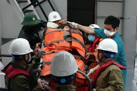 Đưa bệnh nhân lên tàu SAR 274 để vào đất liền. (Ảnh: TTXVN phát) 