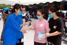 Thanh niên tình nguyện tại Hội đồng thi trường Trung học Phổ thông Trần Hưng Đạo (thành phố Nam Định, tỉnh Nam Định) hướng dẫn thí sinh sát khuẩn tay trước khi vào thi. (Ảnh: Nguyễn Lành/TTXVN) 