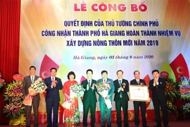 Thừa ủy quyền của Chủ tịch nước, Thường trực Tỉnh ủy, Hội đồng Nhân dân, Ủy ban Nhân dân tỉnh Hà Giang trao Quyết định của Thủ tướng Chính phủ công nhận thành phố Hà Giang hoàn thành nhiệm vụ xây dựng nông thôn mới 2019. (Ảnh: Minh Tâm/TTXVN) 