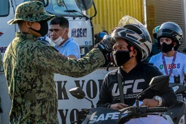 Kiểm tra thân nhiệt người đi đường nhằm phát hiện và ngăn chặn kịp thời dịch COVID tại một trạm kiểm soát giữa thành phố Quezon và tỉnh Rizal ngày 17/3/2020. (Nguồn: THX/TTXVN) 