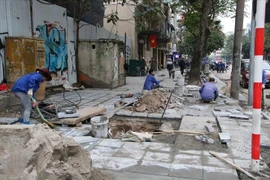 Công nhân lát đá vỉa hè tại Liễu Giai (quận Ba Đình, Hà Nội) khẩn trương thực hiện công việc trong giá rét để kịp tiến độ chủ đầu tư giao. (Ảnh: Minh Nghĩa/TTXVN) 