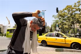 Một người đàn ông đổ nước lên đầu giải nhiệt dưới trời nắng gắt tại Tehran, Iran ngày 11/7/2023. (Ảnh: AFP/TTXVN)