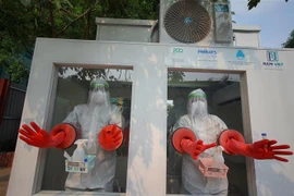 Các nhân viên y tế đang thao tác trước khi tiến hành lấy mẫu trong cabin lấy mẫu xét nghiệm được đưa vào sử dụng tại huyện Tân Yên( Bắc Giang). (Ảnh: Danh Lam/TTXVN) 