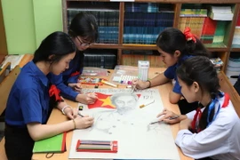 Nhóm học sinh Trường song ngữ Lào-Việt Nam Nguyễn Du vẽ bức họa về Bác Hồ. (Ảnh: Xuân Tú/TTXVN)
