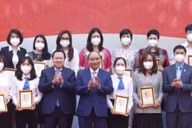 Chủ tịch nước Nguyễn Xuân Phúc tặng ảnh chân dung Chủ tịch Hồ Chí Minh cho các cá nhân có thành tích xuất sắc của Tập đoàn Dệt may Việt Nam. (Ảnh: Thống Nhất/TTXVN) 