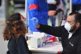 Nhân viên y tế lấy mẫu xét nghiệm COVID-19 cho học sinh tại New York, Mỹ ngày 8/10/2020. (Ảnh: AFP/TTXVN) 