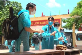 Các công dân tiến hành sát khuẩn khi vừa đến khu cách ly của Trung đoàn Bộ binh 126. (Ảnh: Đinh Tuấn/TTXVN) 