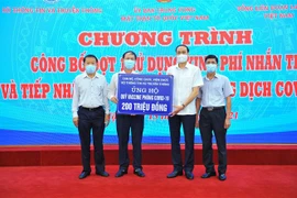 Đại diện Bộ Thông tin và Truyền thông trao tượng trưng số tiền 200 triệu đồng ủng hộ Quỹ vaccine phòng COVID-19. (Ảnh: Minh Đức/TTXVN) 