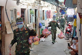 Cán bộ, chiến sỹ Trung đoàn 31, Sư đoàn 309 (Quân đoàn 4) chuyển quà cho nhân dân vùng dịch ở phường 16, Quận 8, TP Hồ Chí Minh. (Ảnh: Thanh Vũ/TTXVN) 