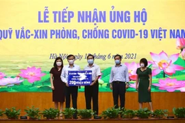 Thứ trưởng Bộ Lao động-Thương binh và Xã hội Lê Tấn Dũng (giữa) trao ủng hộ Quỹ cho Phó Tổng Giám đốc Kho bạc nhà nước Nguyễn Quang Vinh. (Ảnh: Hoàng Hiếu/TTXVN) 