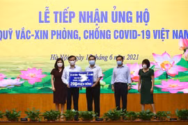 Thứ trưởng Bộ Lao động-Thương binh và Xã hội Lê Tấn Dũng (giữa) trao ủng hộ Quỹ cho Phó Tổng Giám đốc Kho bạc nhà nước Nguyễn Quang Vinh. (Ảnh: Hoàng Hiếu/TTXVN) 