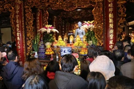 Người dân lễ phật A di đà bằng đá là một trong những bảo vật quốc gia tại chùa Phật Tích. (Ảnh: Thanh Thương/TTXVN)