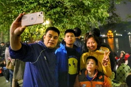 Cả gia đình cùng chụp ảnh lưu niệm tại Hồ Gươm trước thời khắc đón giao thừa, bước sang Năm mới. (Ảnh: Tuấn Đức/TTXVN)